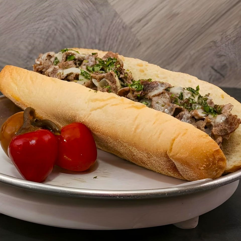 A Familia Pizzeria cheesesteak sandwich with peppers on a white plate.